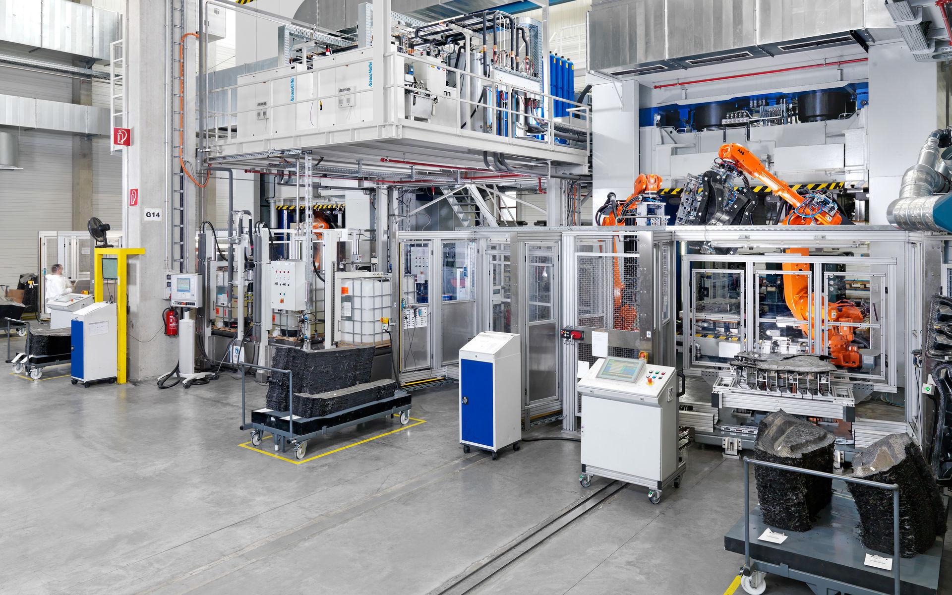 "Planta de producción de alta tecnología de Fritzmeier Composite, con una gran máquina, un robot industrial y otros equipos automatizados gestionados por el sistema MES."