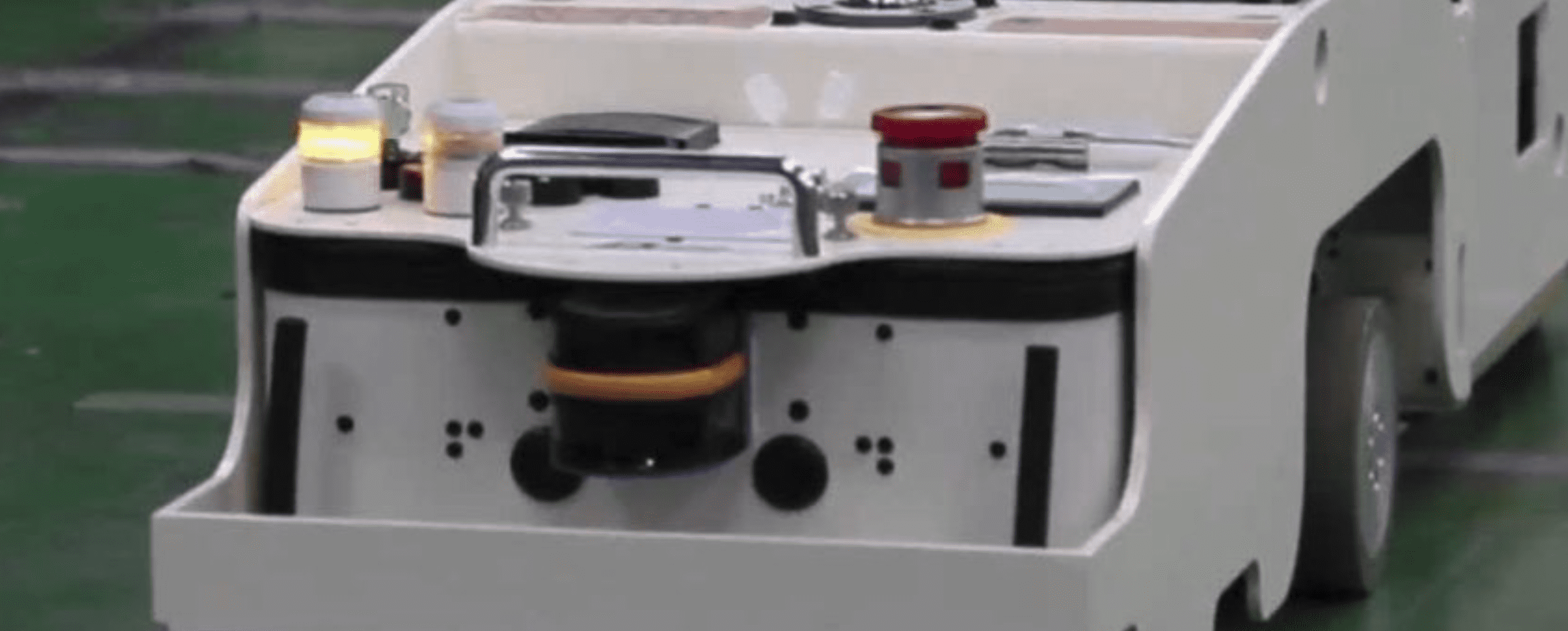 Un Vehículo de Guiado Automático (AGV) blanco en un entorno industrial.