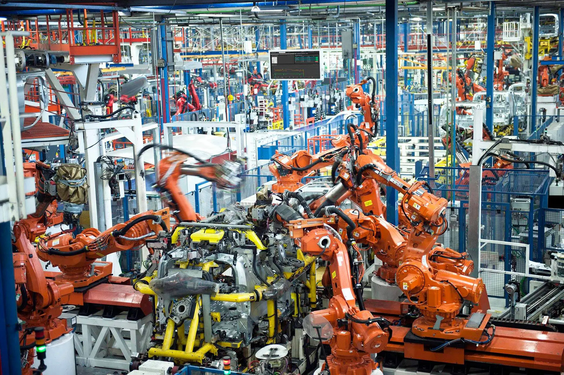 "Línea de producción altamente automatizada en la planta de SEAT, con numerosos robots industriales de color naranja trabajando en el ensamblaje de carrocerías."