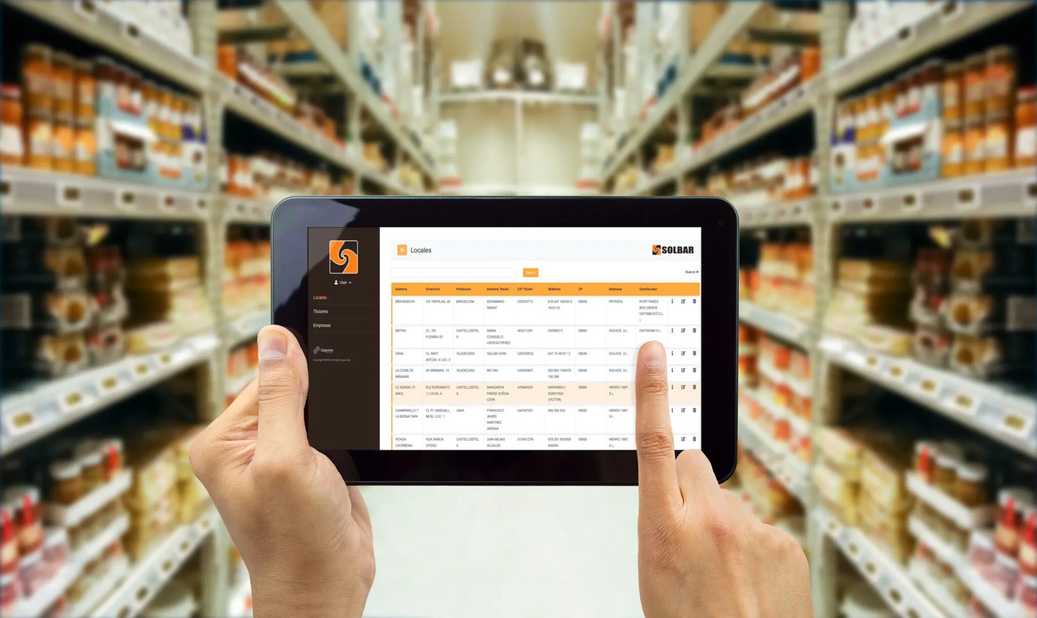 "Una persona usando la plataforma GMAO GeTag en una tablet, que muestra una lista de locales y datos de negocio, ilustrando la solución de digitalización implementada por Geprom para Solbar."
