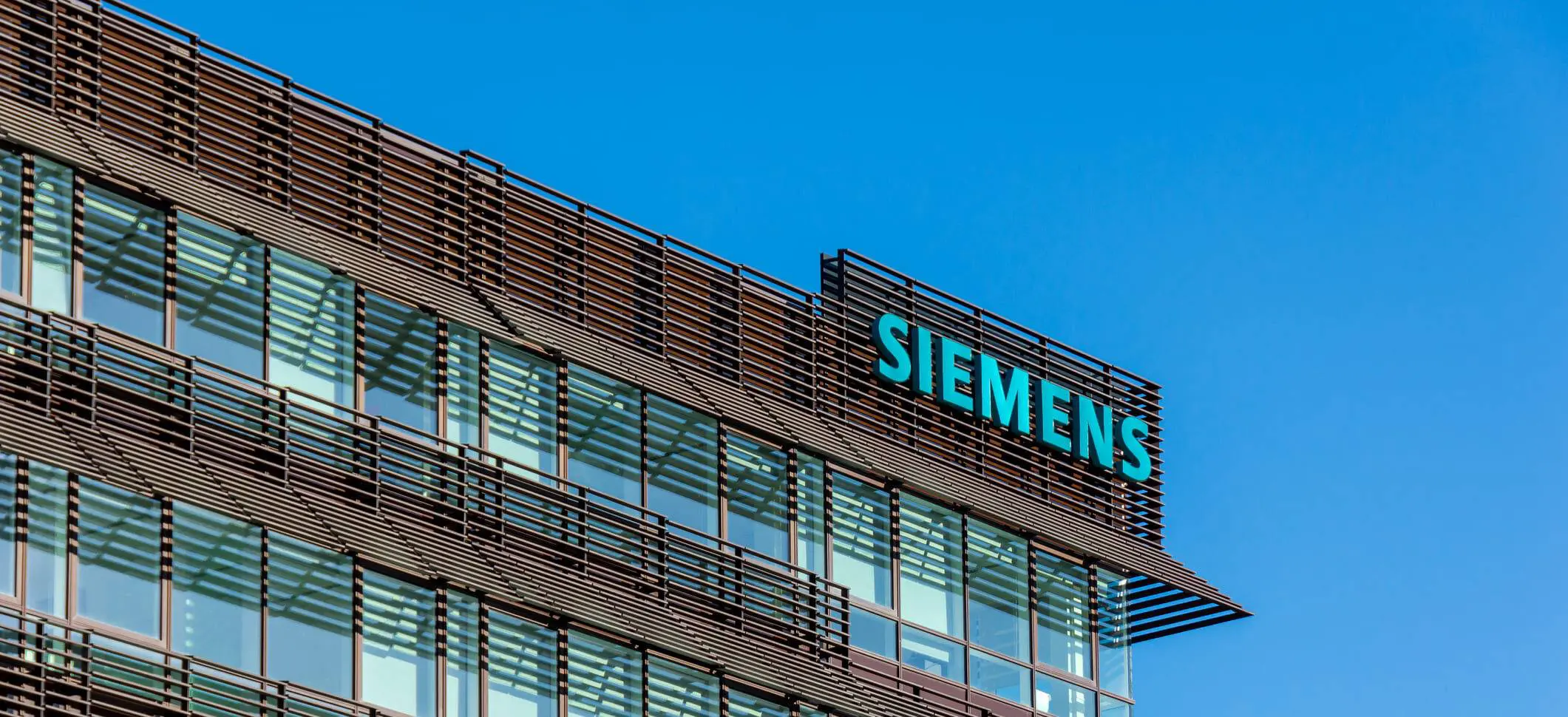 "Fachada de un edificio de oficinas moderno con el logo de Siemens, la empresa cuya tecnología de automatización fue implementada en el caso de éxito."