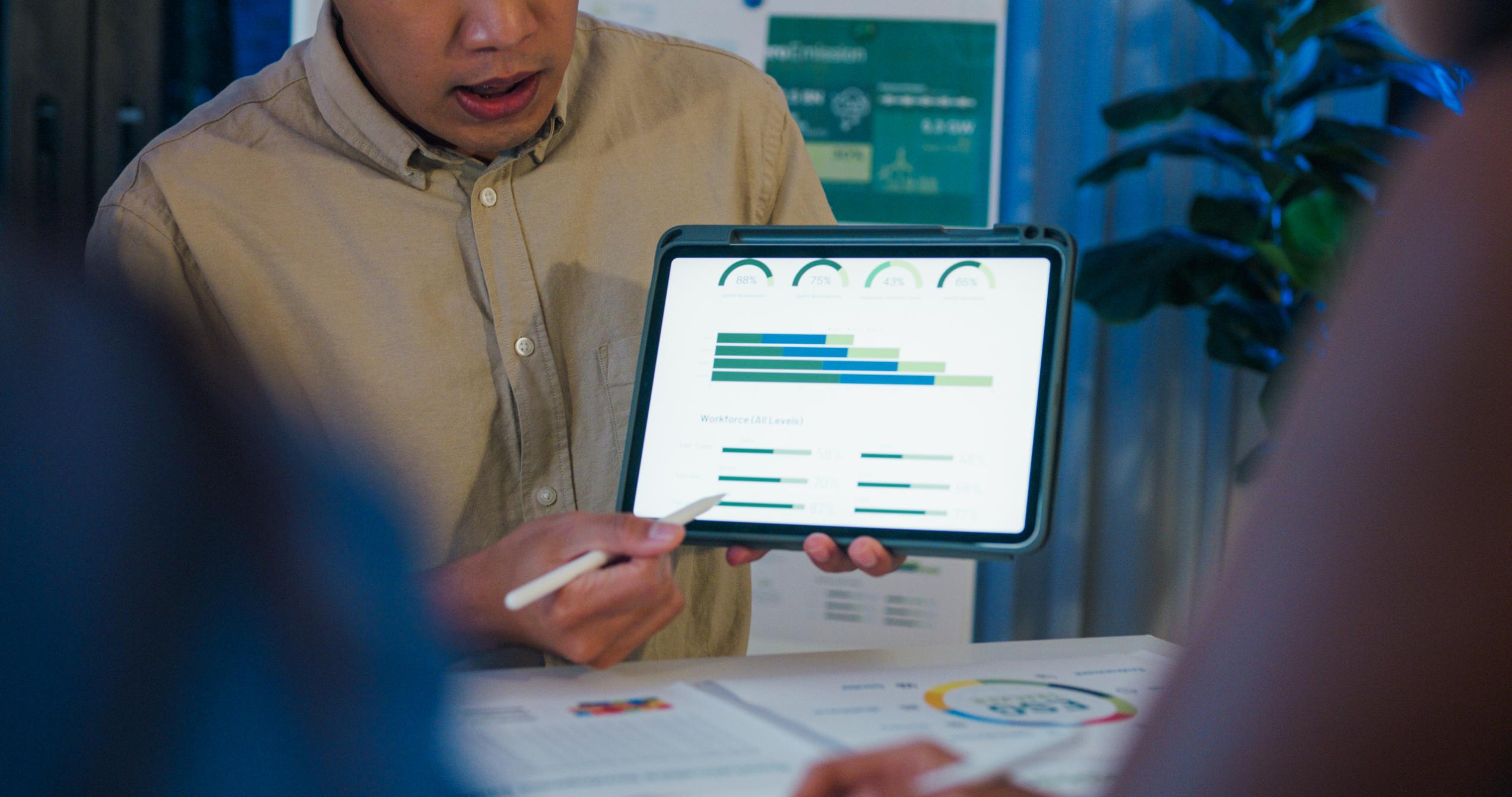 Profesional mostrando en una tablet gráficos de rendimiento y métricas, representando el uso estratégico de datos en entornos industriales.