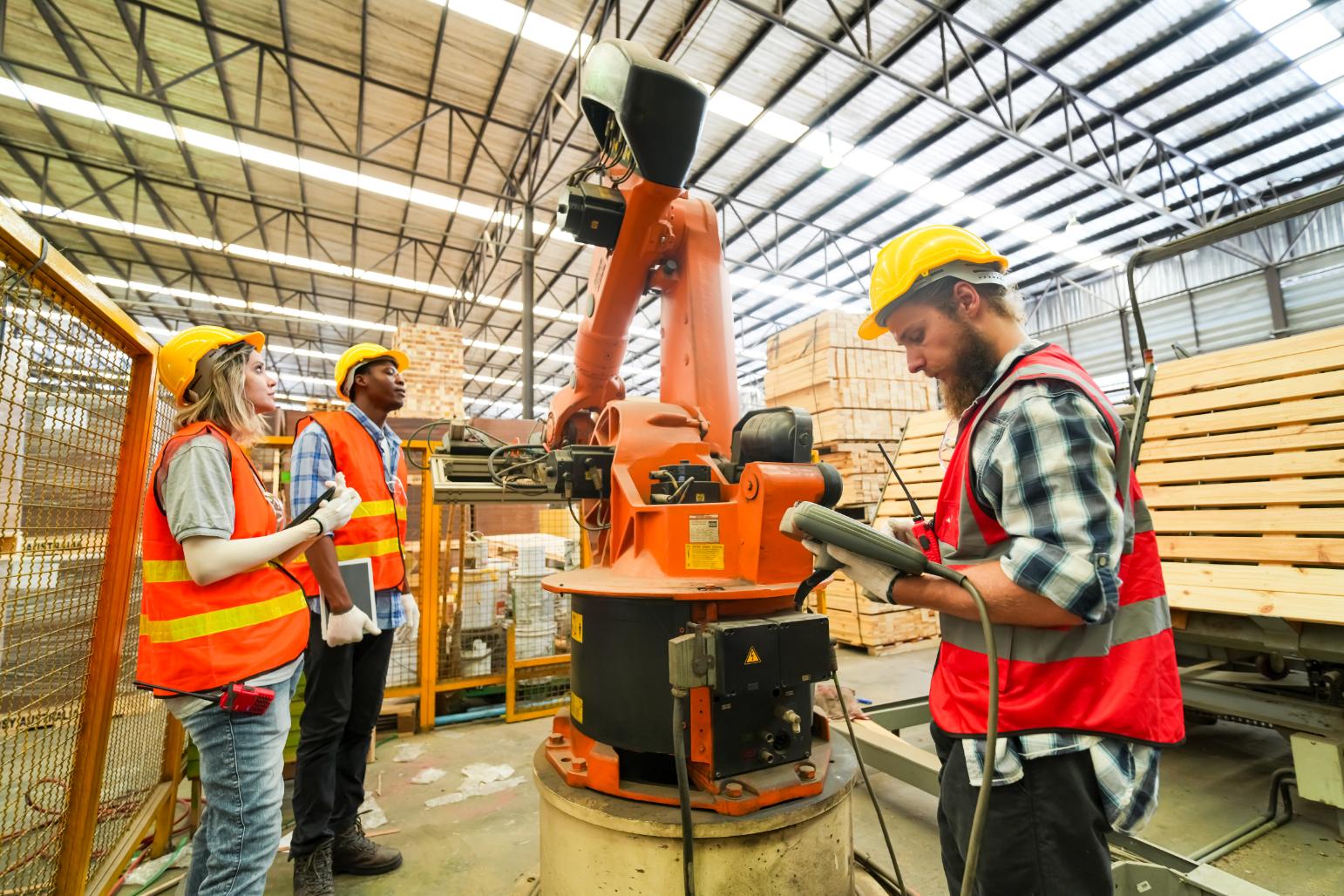 Equipo de operarios programando un robot industrial en una planta de manufactura de madera